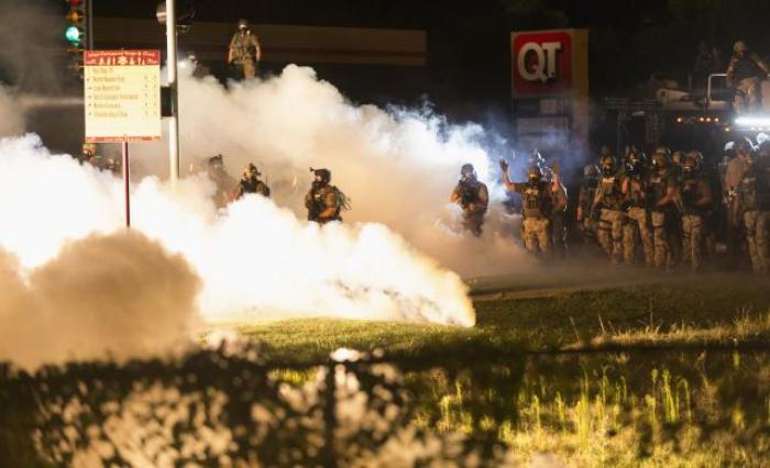 Riot police clear a street with smoke bombs while clashing with demonstrators in Ferguson, Missouri, Aug. 13, 2014.
