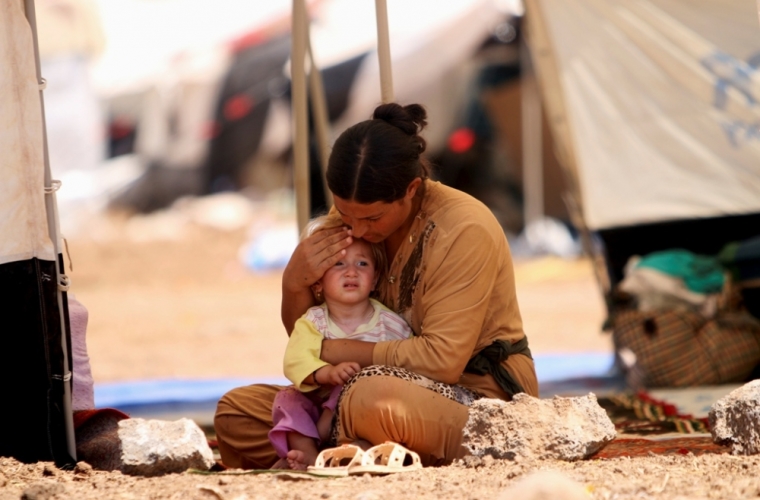 A refugee woman from the minority Yazidi sect, who fled the violence in the Iraqi town of Sinjar, sits with a child inside a tent at Nowruz refugee camp in Qamishli, northeastern Syria Aug. 17, 2014. Proclaiming a caliphate straddling parts of Iraq and Syria, Islamic State militants have swept across northern Iraq, pushing back Kurdish regional forces and driving tens of thousands of Christians and members of the Yazidi religious minority from their homes.