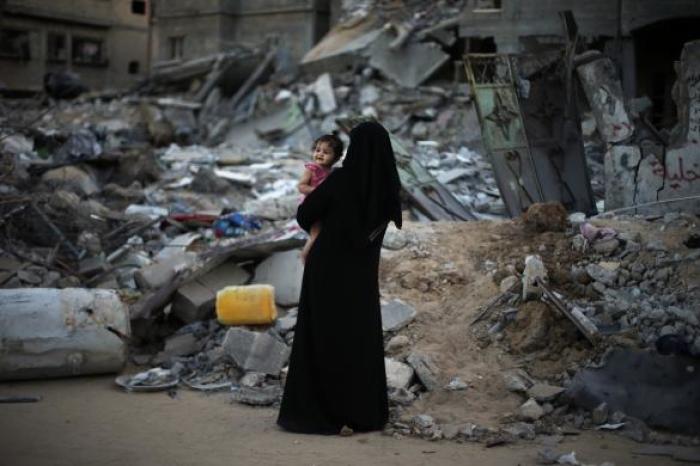 A Palestinian woman holds her daughter as they stand in front of their house, which witnesses said were destroyed in an Israeli offensive, during a 72-hour truce in Beit Hanoun town in the northern Gaza Strip, Aug. 12, 2014.