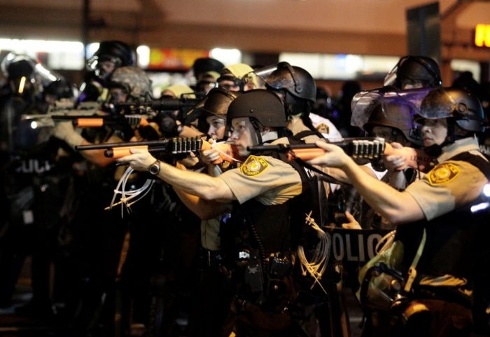 Police officers point their weapons at demonstrators protesting against the shooting death of Michael Brown in Ferguson, Missouri, Aug. 18, 2014.