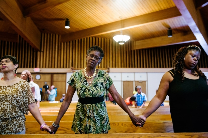 Parishioners hold hands during church services at the Greater St Mark Family Church as the community discusses reactions to the shooting of teenager Michael Brown in Ferguson, Missouri August 17, 2014. The Ferguson police department has come under strong criticism for both the shooting and its handling of its aftermath. On Sunday U.S. Attorney General Eric Holder ordered a federal medical examiner to perform an autopsy, in addition to one being conducted by state medical examiners.