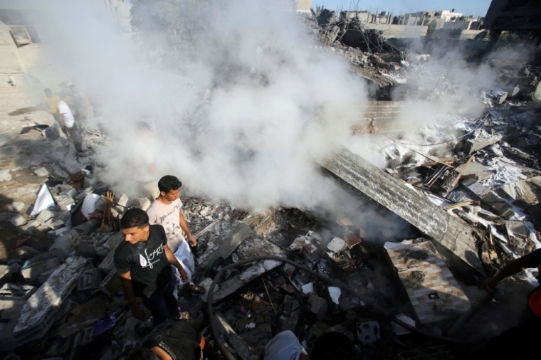 Smoke rises as Palestinians stand atop the rubble of a house, which witnesses said was destroyed in an Israeli air strike, in Rafah in the southern Gaza Strip, Aug. 20, 2014. Hamas militants in the Gaza Strip fired rockets at Israel for a second day on Wednesday after fighting resumed with the collapse of truce talks and an Israeli air strike that killed three people in Gaza.