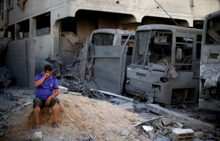 A Palestinian sits next to buses that witnesses said were destroyed during an Israeli airstrike in Gaza City, Aug. 20, 2014. Hamas militants in the Gaza Strip fired rockets at Israel for a second day on Wednesday after fighting resumed with the collapse of truce talks and an Israeli air strike that killed three people in Gaza.