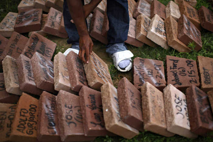 A teenager picks through paving stones painted with the names of kids killed by violence as they repair a memorial for the victims of violence in Chicago, Illinois, on Aug. 3, 2011.
