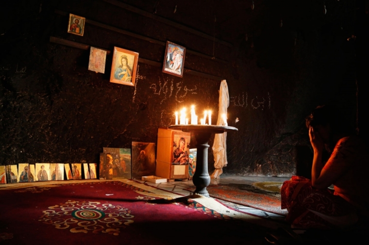 A woman prays inside a damaged church in Maaloula August 21, 2014. Residents of Maaloula, a Christian town in Syria, call on other Christian groups and minorities to stand up to the radicalism that is sweeping across Syria and Iraq. The town was regained by Syrian Army forces in April from Islamic militants, and several months later life is slowly returning to the town.