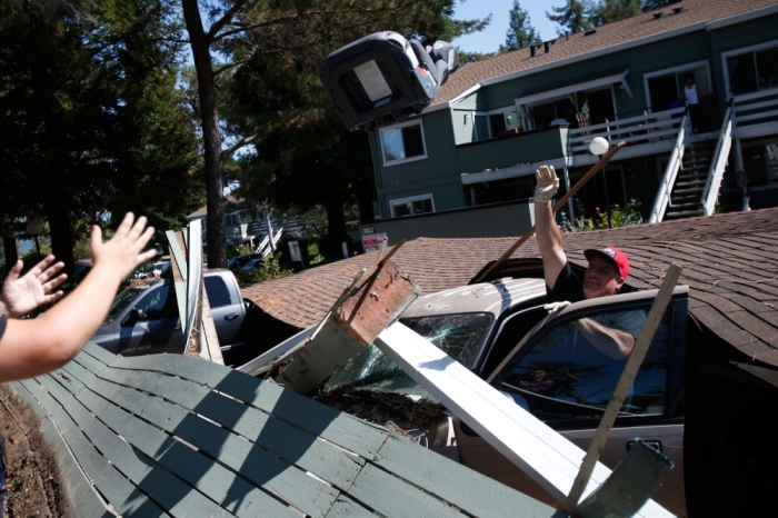 Karl Luchsinger (C) removes a car seat from a vehicle crushed by a collapsed parking structure in Napa, California August 24, 2014. A 6.0 earthquake rocked wine county north of San Francisco early Sunday, injuring dozens of people, damaging historical buildings, setting some homes on fire and causing power outages around the picturesque town of Napa. The quake, the biggest in the region in 25 years, jolted many residents out of bed when it hit at 3:20 a.m. (1020 GMT). It was centered 6 miles (10 km) south of the city of Napa.