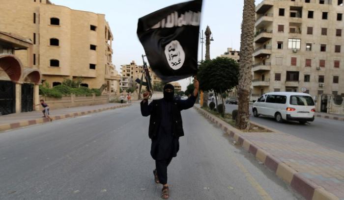 A member of the Islamic State in Iraq and the Levant waves an ISIS flag.