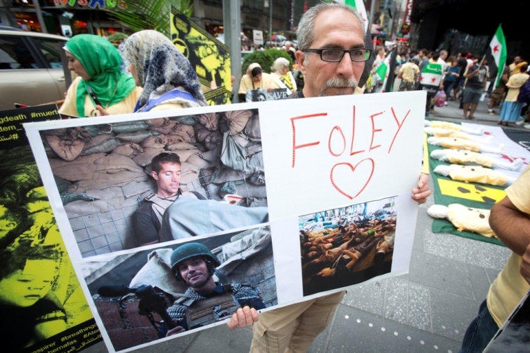 A man holds up a sign in memory of U.S. journalist James Foley during a protest against the Assad regime in Syria in Times Square in New York, Aug. 22, 2014. Foley, who was abducted in Syria in late 2012, was beheaded by a masked member of the Islamic State in an act filmed in a video released on Aug. 19 that also threatened a second American journalist, Steven Sotloff.
