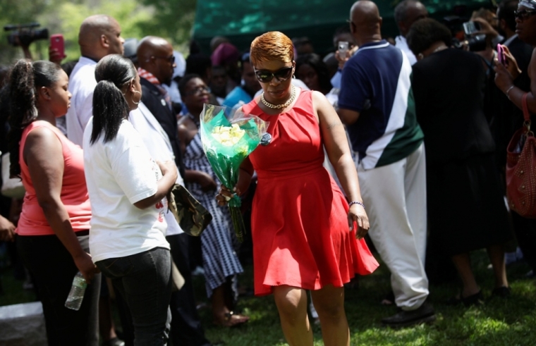 Lesley McSpadden (C) leaves the burial service for her son Michael Brown with a bouquet of flowers at St. Pete's Cemetery in St. Louis, Missouri, Aug. 25, 2014. Family and supporters on Monday celebrated the life of Michael Brown, a black teenager slain by police in Ferguson, Missouri, with a music-filled funeral service and calls to remember him with peace and political change.