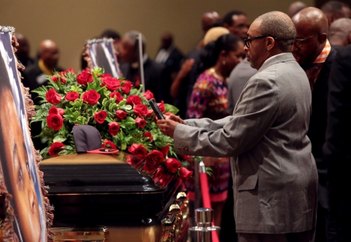 Director Spike Lee takes a photo of a St. Louis Cardinals baseball cap on top of Michael Brown's casket at Friendly Temple Missionary Baptist Church in St. Louis, Missouri, Aug. 25, 2014.