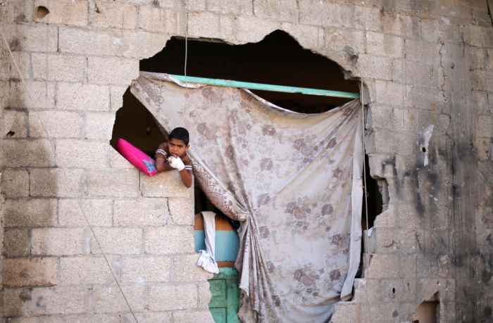 A Palestinian boy looks out of his damaged house after a ceasefire was declared, in the east of Khan Younis in the southern Gaza Strip August 27, 2014. The open-ended ceasefire in the Gaza war between Israel and the Palestinians held on Wednesday as Prime Minister Benjamin Netanyahu faced strong criticism in his country's newspapers over a campaign in which no clear victor emerged.