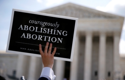 A pro-life activist with a group celebrating the U.S. Supreme Court's ruling striking down a Massachusetts law that mandated a protective buffer zone around abortion clinics, holds up a sign reading 'Courageously Abolishing Abortion,' outside the Court in Washington, June 26, 2014. On a 9-0 vote, the court said the 2007 law violated the freedom of speech rights of anti-abortion protesters under the First Amendment of the U.S. Constitution in preventing them from standing on the sidewalk and speaking to people entering the clinics.