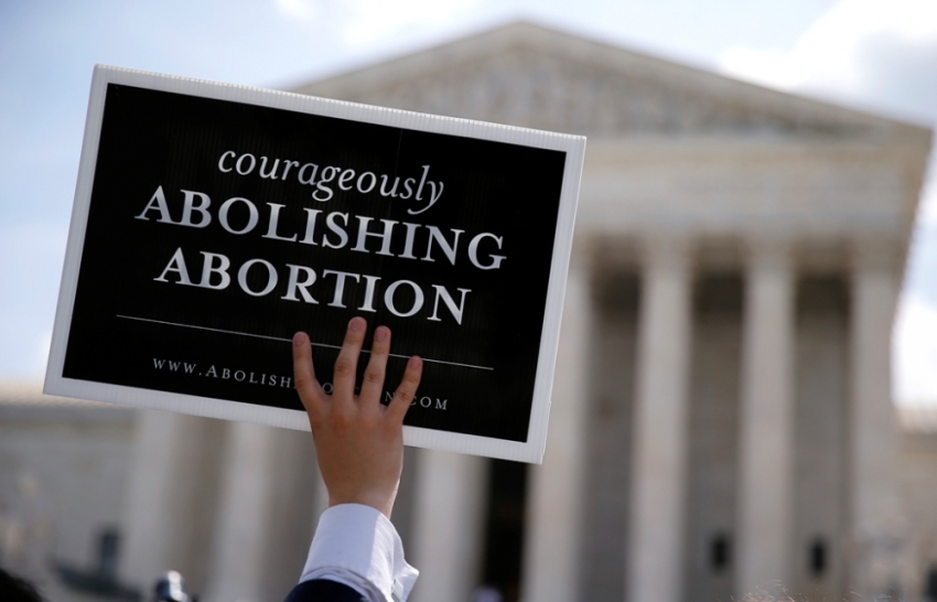 A pro-life activist with a group celebrating the U.S. Supreme Court's ruling striking down a Massachusetts law that mandated a protective buffer zone around abortion clinics, holds up a sign reading 