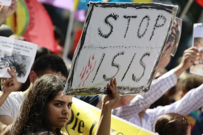 A woman holds a placard denouncing ISIS.