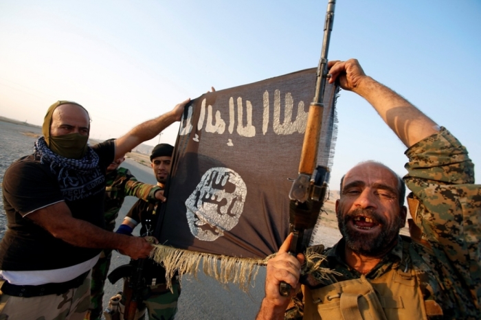 Iraqi Shiite militia fighters hold the Islamic State flag as they celebrate after breaking the siege of Amerli by Islamic State militants, Sept. 1, 2014.