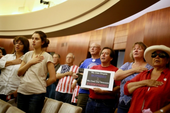 Residents say the Pledge of Allegiance during a meeting by the Escondido City Council discussing whether or not to allow Southwest Key, a leading shelter provider for unaccompanied immigrant children, to open a shelter in Escondido, July 22, 2014.