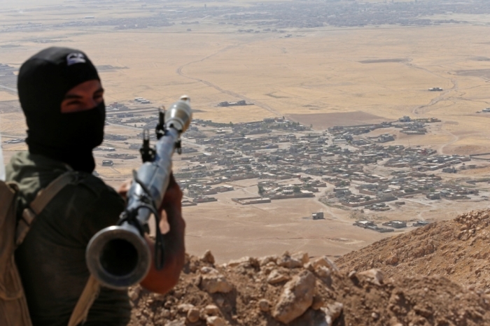 A Kurdish Peshmerga fighter holds a a rocket-propelled grenade launcher as he takes up position in an area overlooking Baretle village (background), which is controlled by the Islamic State, in Khazir, on the edge of Mosul, Sept. 8, 2014. The Kurdish fighters are firing from an area they had retaken from the Islamic State, on Bashiqah mountain.