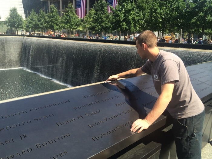 Robert Peacock, 26, of KCC Fabrications, shines a portion of the bronze panel on one of the Memorial pools at the National September 11 Memorial in downtown New York City, Sept. 10, 2014.