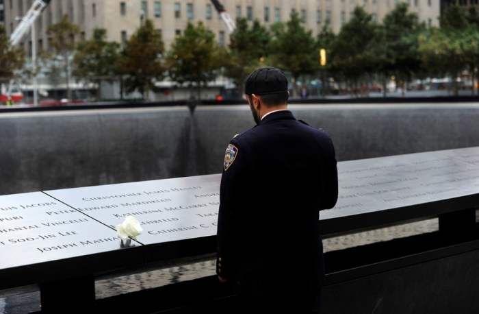 New York City Police Champlain Khalid Laitif stands at the edge of the North Pool during memorial observances on the 13th anniversary of the 911 attacks at the site of the World Trade Center in New York, Sept. 11, 2014. Politicians, dignitaries and victims' relatives were gathering in New York, Washington and Pennsylvania on Thursday to commemorate the nearly 3,000 people killed in al Qaeda's attack on the United States 13 years ago on Sept. 11, 2001.