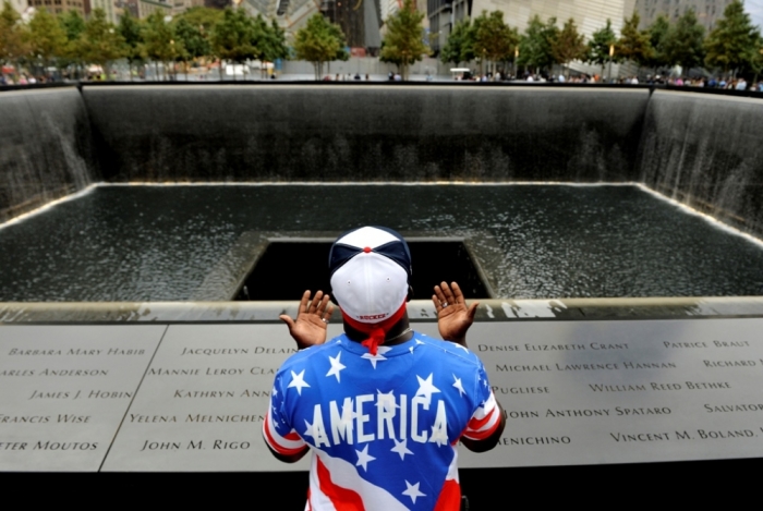 Albert Biatta, of Queens, New York, prays while standing in front of the inscribed name of his uncle, Antoine Biatta, at the edge of the North Pool during memorial observances held at the site of the World Trade Center in New York, Sept. 11, 2014.
