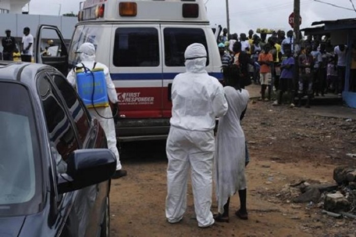 Health workers bring a woman suspected of having contracted Ebola virus to an ambulance in front of a crowd in Monrovia, Liberia, Sept. 15, 2014.
