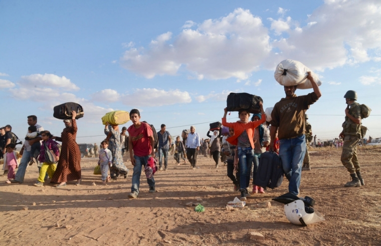 Syrian Kurds walk with their belongings after crossing into Turkey at the Turkish-Syrian border, near the southeastern town of Suruc in Sanliurfa province, September 20, 2014. About 60,000 Syrian Kurds fled into Turkey in the space of 24 hours, a deputy prime minister said on Saturday, as Islamic State militants seized dozens of villages close to the border. Turkey opened a stretch of the frontier on Friday after Kurdish civilians fled their homes, fearing an imminent attack on the border town of Ayn al-Arab, also known as Kobani. A Kurdish commander on the ground said Islamic State had advanced to within 15 km (9 miles) of the town. Picture taken September 20, 2014.