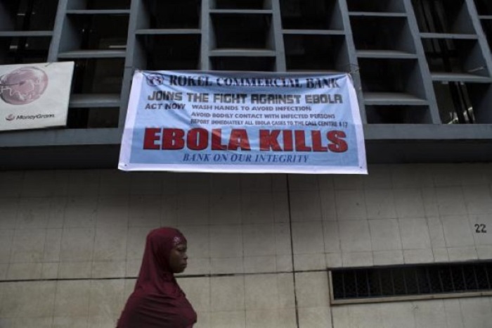 A woman passes a sign posted in an awareness campaign against the spread of Ebola in Freetown, Sierra Leone September 18, 2014 in a handout photo provided by UNICEF.