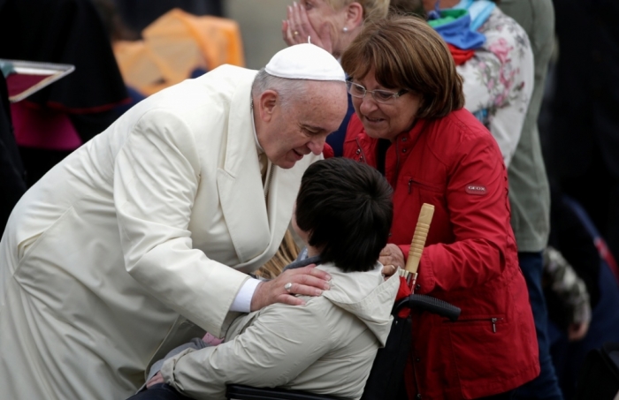 Pope Francis touches a sick person at the end of his weekly audience in Saint Peter's Square at the Vatican, Rome, Italy, September 24, 2014.
