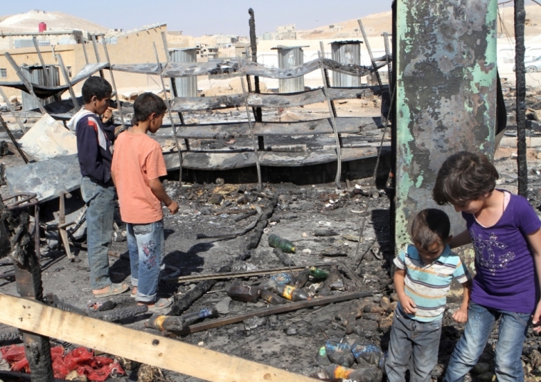 Children look at damage and the remains of tents for Syrian refugees that were burnt in the fighting between Lebanese army soldiers and Islamist militants in the Sunni Muslim border town of Arsal, in eastern Bekaa, August 9, 2014.