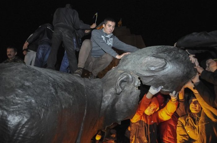 People react after a statue of Soviet state founder Vladimir Lenin was toppled by protesters during a rally organized by pro-Ukraine supporters in the centre of the eastern Ukrainian town of Kharkiv September 28, 2014.