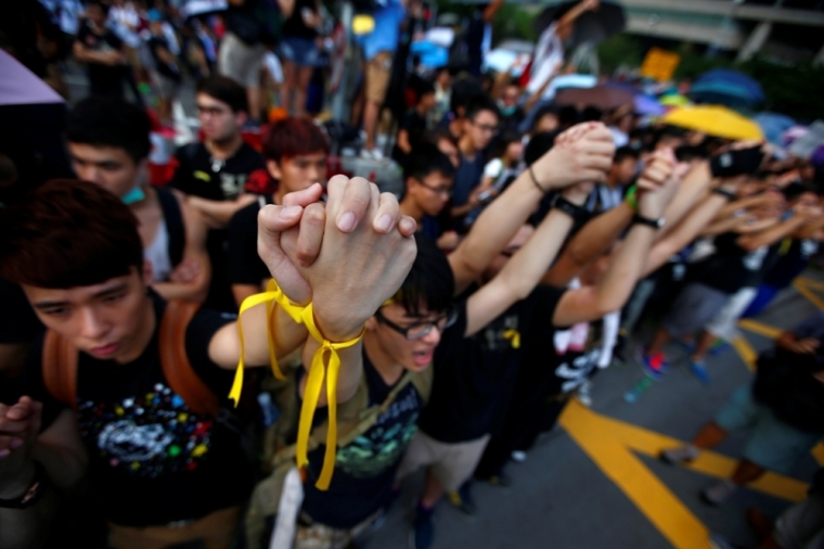 Protesters hold their hands as they gather around the Golden Bauhinia Square during an official flag raising ceremony to commemorate the Chinese National Day in Hong Kong, October 1, 2014. Tens of thousands of pro-democracy protesters extended a blockade of Hong Kong streets on, stockpiling supplies and erecting makeshift barricades ahead of what some fear may be a push by police to clear the roads before Chinese National Day.