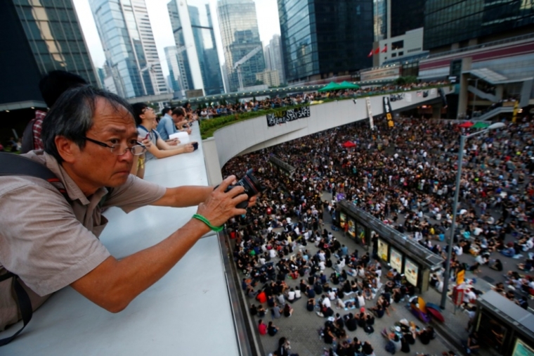 A man takes pictures as protesters block the main street to the financial Central district outside of the government headquarters building in Hong Kong, October 1, 2014. Thousands of pro-democracy protesters thronged the streets of Hong Kong on Wednesday, ratcheting up pressure on the pro-Beijing government that has called the action illegal, with both sides marking uneasy National Day celebrations.