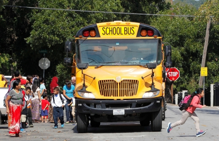 Students disembark from a school bus outside The Ivy Apartments, where a man diagnosed with the Ebola virus was staying in Dallas, Texas October 1, 2014.