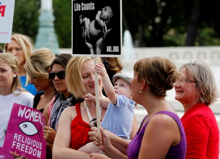 An anti-abortion protestor holds her child as activists celebrate the U.S. Supreme Court's ruling, striking down a Massachusetts law that mandated a protective buffer zone around abortion clinics, as the demonstrators stand outside the Court in Washington, June 26, 2014.
