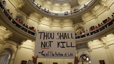 An anti-abortion protester holds a placard as protesters line the railing on the second floor of the rotunda of the State Capitol as the state Senate meets to consider legislation restricting abortion rights in Austin, Texas July 12, 2013.