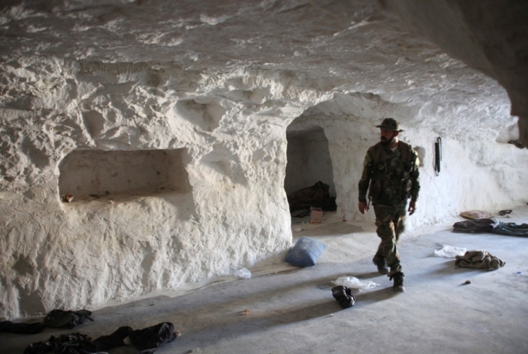 A member of the forces of Syria's President Bashar al-Assad inspects a cave used by rebel fighters in Zor al-Mahruqa village, after the forces said they regained control of the area and its surrounding hills, in the Hama countryside, October 6, 2014.