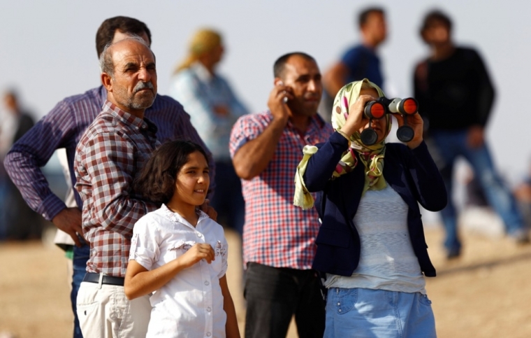 Turkish Kurds watch over Syrian town of Kobani as they stand near Mursitpinar border crossing in the southeastern Turkish town of Suruc in Sanliurfa province, October 3, 2014. Kurdish fighters defending a Syrian border town warned on Friday of a likely massacre by Islamic State insurgents as the Islamists encircled the town with tanks and bombarded its outskirts with artillery fire. Turkey said it would do what it could to prevent Kobani, a predominantly Kurdish town just over its southern border, from falling into Islamic State hands but stopped short of committing to any direct military intervention.