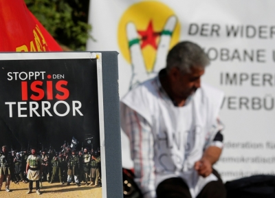 A Kurdish protester sits behind a sign reading 'STOP ISIS terror' in front of the United Nations headquarters in Vienna, Austria, October 9, 2014. A group of Kurdish people living in Austria are on hunger strike since Monday in solidarity for Syrian Kurds who are fighting to defend the Syrian-Turkey border town of Kobane from Islamic State militants.