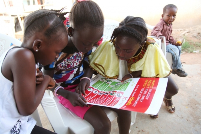 Girls look at a poster, distributed by UNICEF, bearing information on and illustrations of best practices that help prevent the spread of Ebola virus disease, in the city of Voinjama, in Lofa County, Liberia, in this April 2014 UNICEF handout photo. deaths.