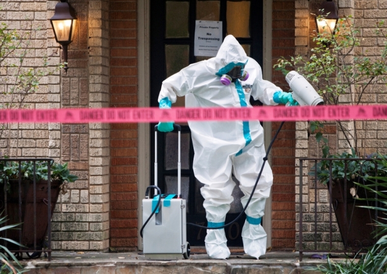A member of the CG Environmental HazMat team disinfects the entrance to the residence of a health worker at the Texas Health Presbyterian Hospital who has contracted Ebola in Dallas, Texas, October 12, 2014.