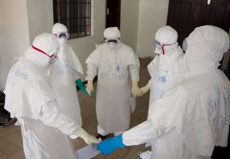 Health workers wearing protective equipment hold hands as they pray at the start of their shift before entering the Ebola treatment centre at the Island Clinic in Monrovia, September 30, 2014.