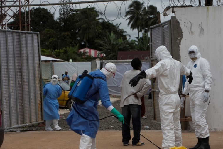 Health workers wearing protective equipment are disinfected outside the Island Clinic in Monrovia, September 30, 2014, where patients are treated for Ebola.