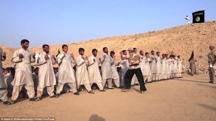 Islamic State recruits stand in line and wait to get kicked in the midsection by an ISIS combat instructor as a part of their jihad training at an Islamic State training camp in Nineveh City.