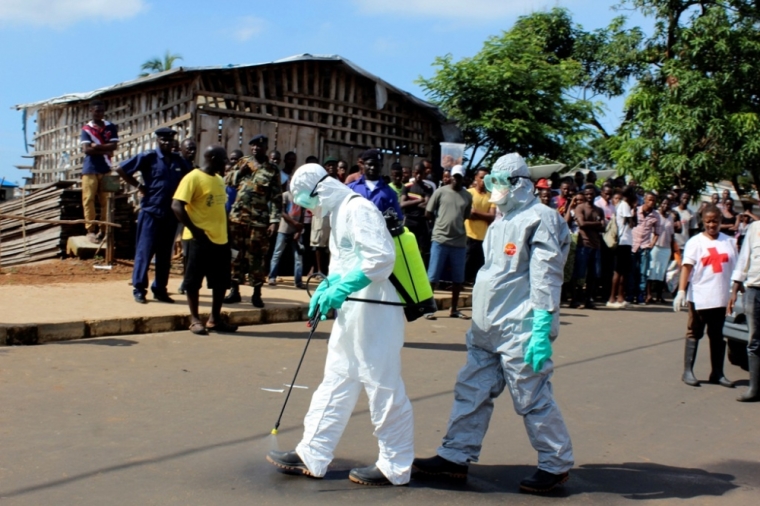 Health workers spray themselves with chlorine disinfectants after removing the body a woman who died of Ebola virus in the Aberdeen district of Freetown, Sierra Leone, October 14, 2014.