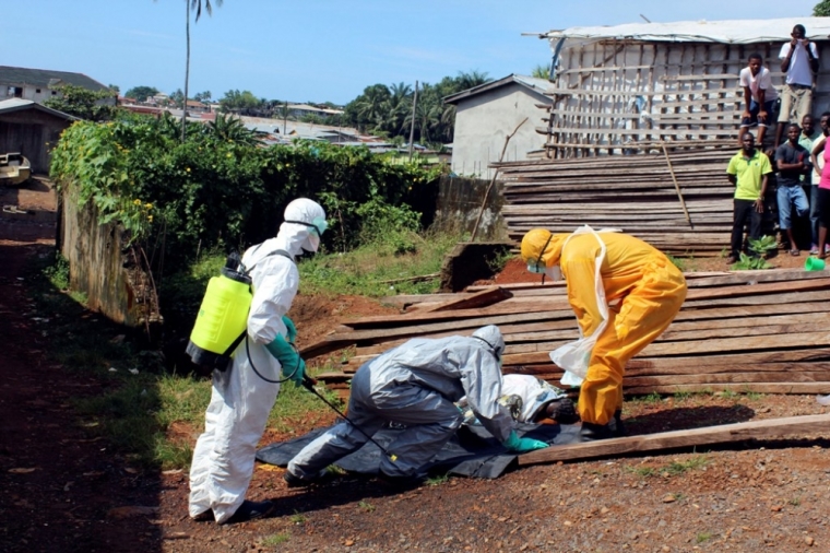 Health workers remove the body a woman who died from the Ebola virus in the Aberdeen district of Freetown, Sierra Leone, October 14, 2014.
