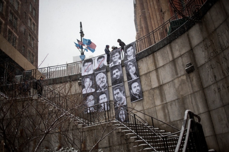 Members of Inside Out Group Action hang an installation outside of the United Nations Headquarters in New York, February 18, 2014. The installation is part of a global participatory art project started by famed street artist and 2011 TED prize winner JR, and features the portraits of 13 Iranian 'prisoners of rights.'