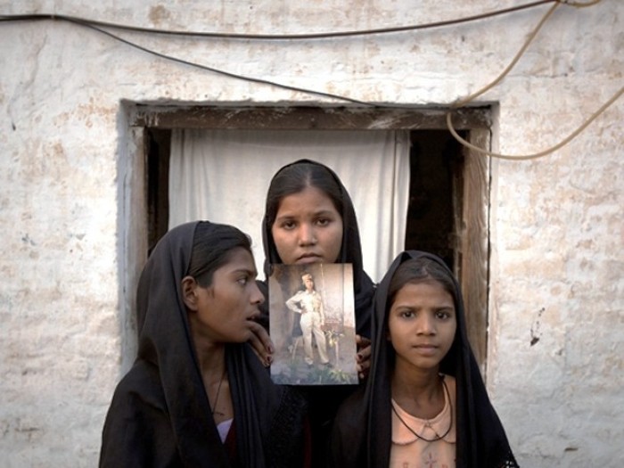 The daughters of Asia Bibi with an image of their mother, standing outside their residence in Sheikhupura on November 13, 2010.