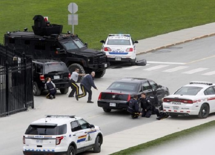 Police officers take cover near Parliament Hilll following a shooting incident in Ottawa October 22, 2014.