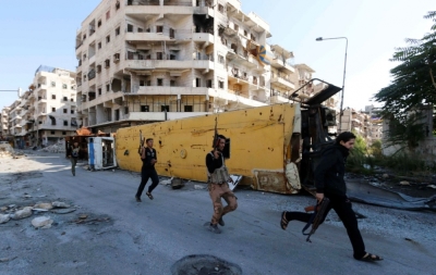 Rebel fighters carry their weapons as they run to avoid snipers at the frontline against forces loyal to Syria's President Bashar al-Assad in Bustan al-Basha neighbourhood of Aleppo, Syria, October 23, 2014.