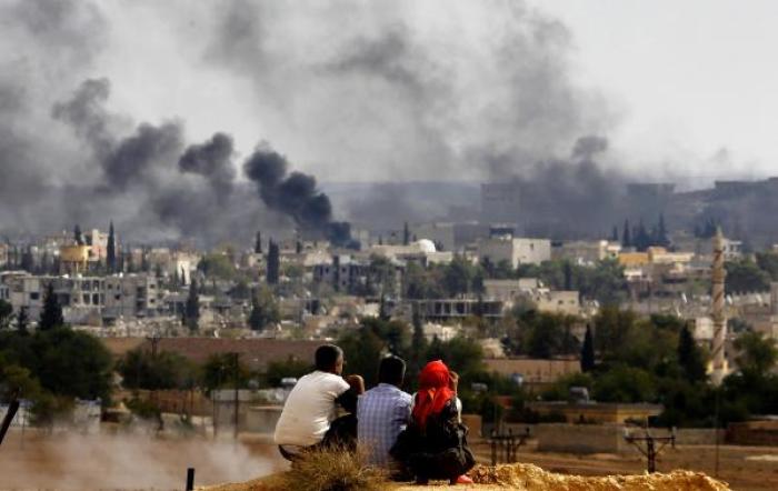 Kurdish refugees from Kobani watch as thick smoke covers the Syrian town of Kobani during fighting between Islamic State and Kurdish Peshmerga forces, as seen from the Mursitpinar crossing on the Turkish-Syrian border in Sanliurfa province October 26, 2014.